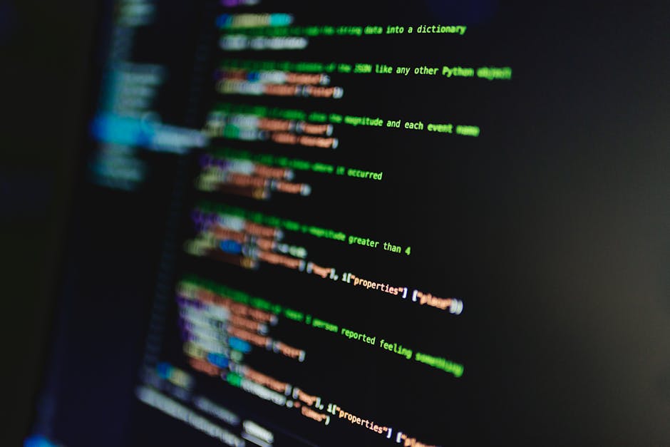 A close-up of a computer screen displaying lines of colorful programming code with green, blue, orange, and purple text on a black background. The interface suggests coding related to software develop